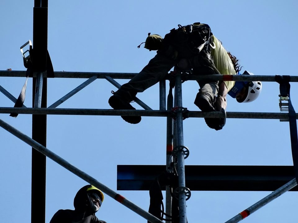 Workers in harnesses working at height on a scaffold